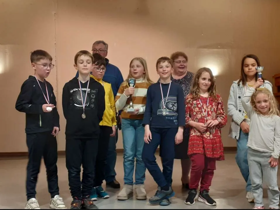 Les jeunes du club posent sur scène avec leurs médailles et un trophée